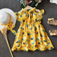 Yellow floral dress with matching shoes and hat on a textured surface