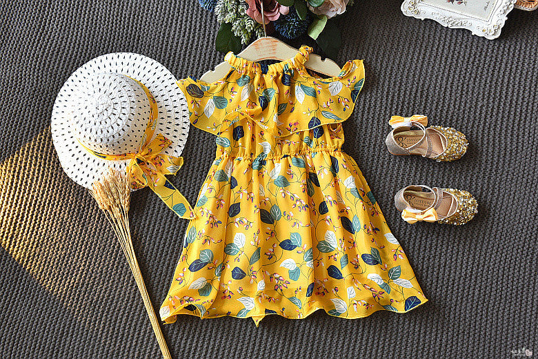 Yellow floral dress with matching shoes and hat on a textured surface