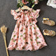 Pink floral dress with matching shoes on a textured surface