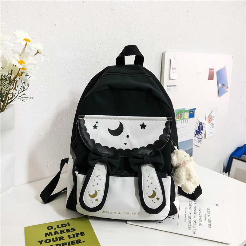 Black backpack with white accents on a desk with a white wall background