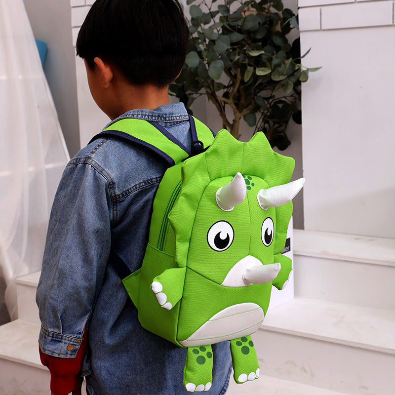 Child wearing a green dinosaur backpack on a white staircase