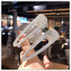 Hand holding two sparkling hair clips with a blurred indoor background