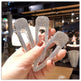 Three sparkling hair clips held by a hand in an indoor setting.
