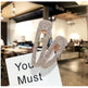 Silver hair clips with rhinestones on a white card with 'You Must' text, blurred restaurant background