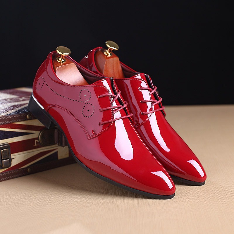 Shiny red dress shoes with gold laces on a dark background