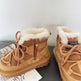 Pair of tan winter boots with white fur lining on a gray surface.