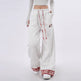 White sweatpants with red plaid accents worn by a person on a white background