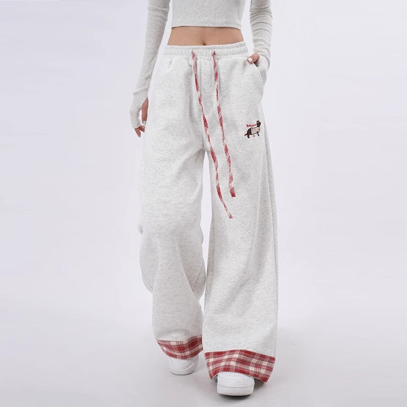 White sweatpants with red plaid accents worn by a person on a white background