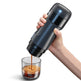 Hand holding a black portable coffee maker pouring coffee into a glass.
