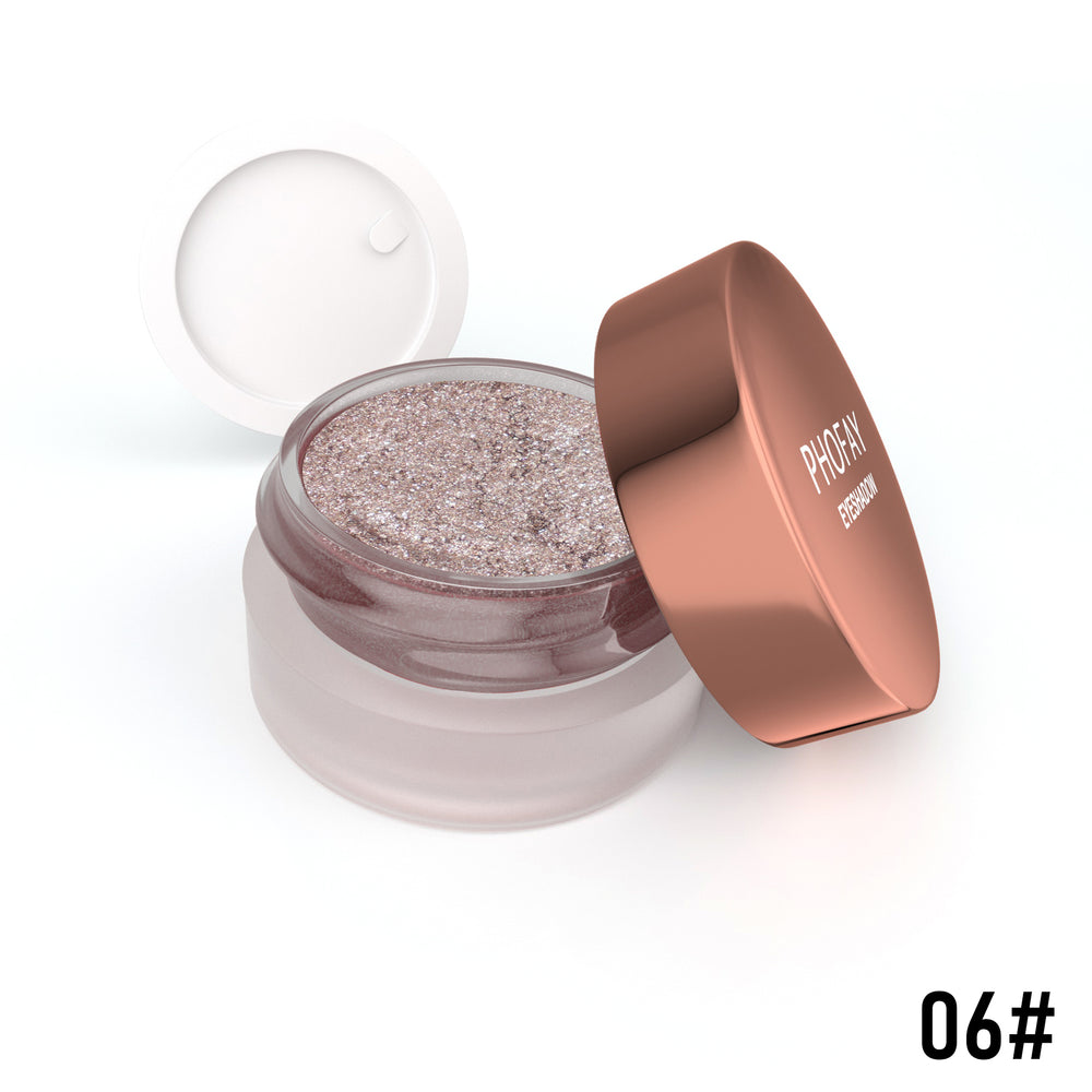 Open jar of glittery makeup with a rose gold lid on a white background