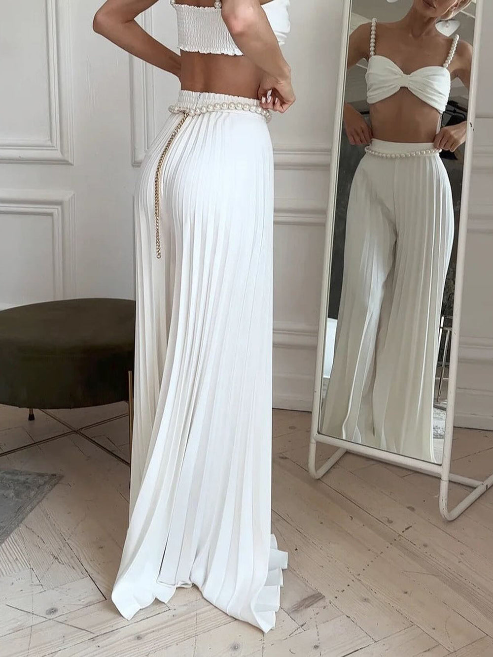 Woman wearing a white outfit with a matching skirt in front of a mirror.