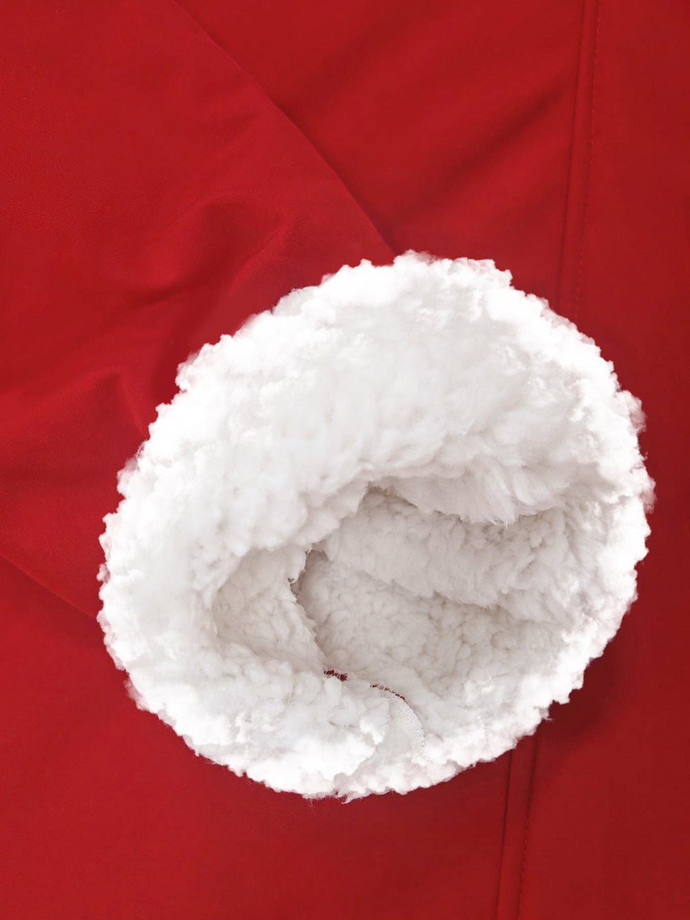 Close-up of a white sherpa or faux-fur trim lining a red garment sleeve or cuff.