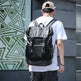 Person wearing a black backpack in front of a geometric-patterned wall.