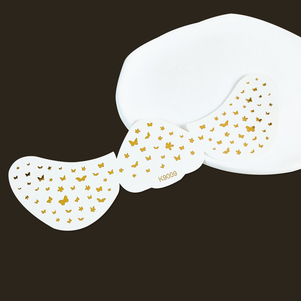 White butterfly-shaped stickers with gold butterfly patterns on a black background