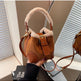 Brown suede handbag with fur trim held by a hand against a neutral background