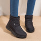 Black ankle boots worn with blue jeans on a beige surface