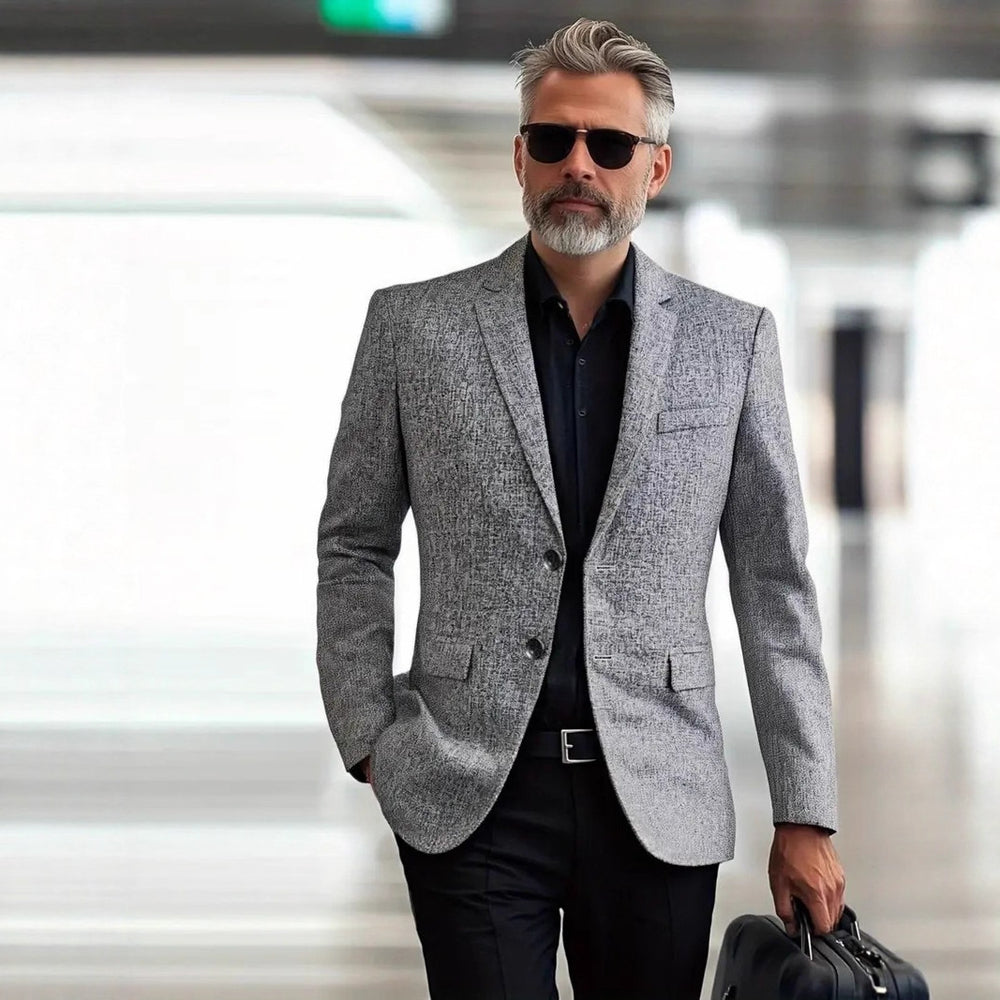 Man wearing a gray blazer and sunglasses in an indoor setting