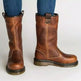 Brown leather boots worn with blue jeans on a white background