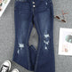 Distressed blue jeans on a gray surface with sneakers and sunglasses.