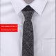 Black patterned tie on a white shirt with a red item number label.