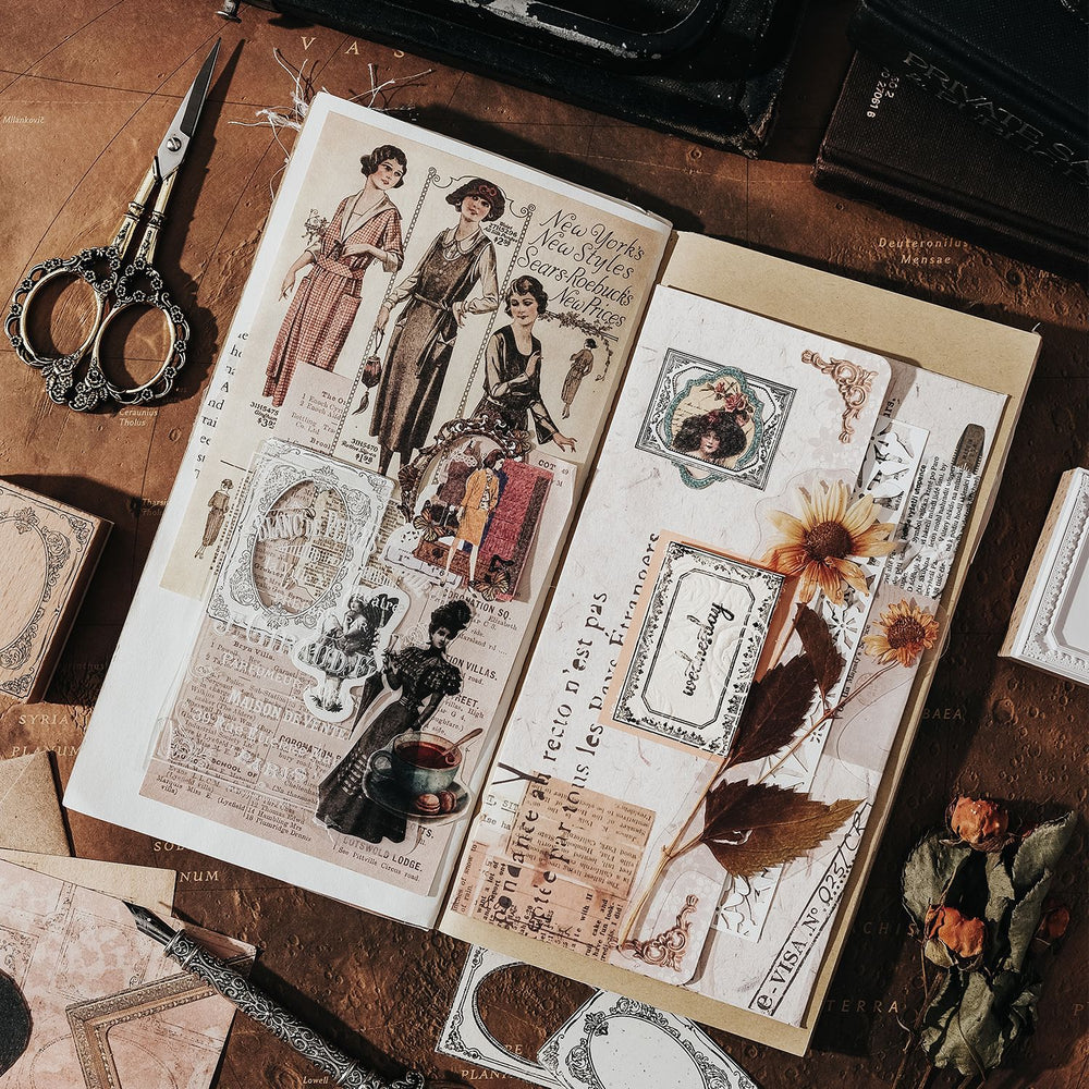 Open book with vintage-style illustrations on a wooden surface with scissors and dried flowers.