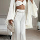 Woman in a white outfit with pearl accessories in a room.
