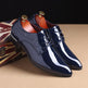 Pair of navy blue patent leather shoes with gold laces on a beige surface.