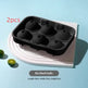 Black 6-cavity ice cube tray on a light blue background with limes.