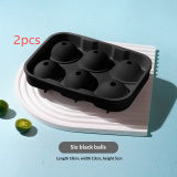 Black 6-cavity ice cube tray on a light blue background with limes.