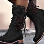 Black suede boots with brown soles worn by a person.