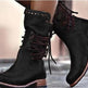 Black suede boots with brown soles worn by a person.