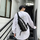 Person wearing a white sweatshirt with a logo and a black backpack, standing on stairs.