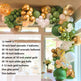 Balloon arch with green, gold, and white balloons in a room with large windows.
