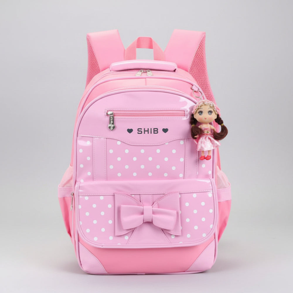 Pink polka dot backpack with a bow and a small doll charm on a white background