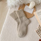 Calza beige su una superficie strutturata con una candela e un biglietto sullo sfondo