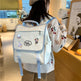 Personne portant un sac à dos blanc avec des bretelles bleues dans un environnement intérieur.