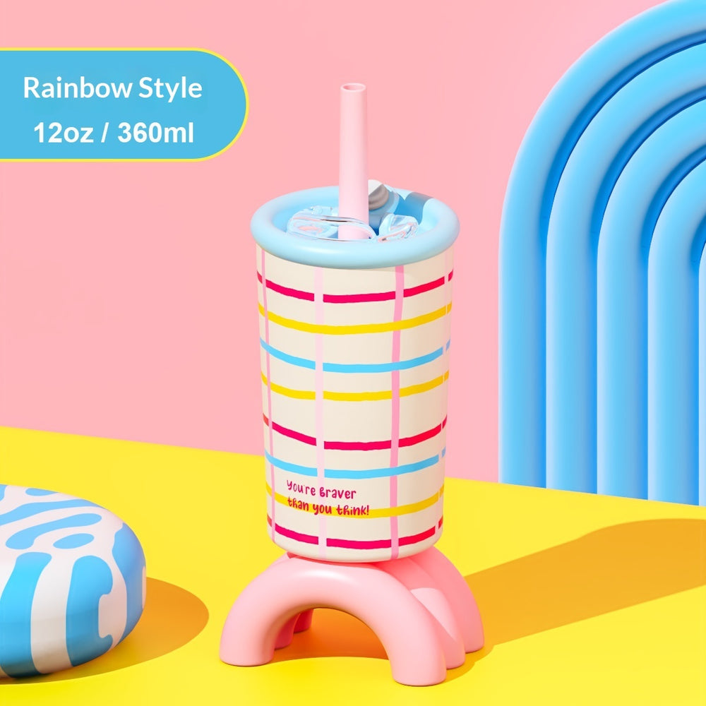 A colorful 12 oz plastic tumbler with a pink stand, featuring rainbow-striped patterns in pink, yellow, blue, and white. It has a light blue rim and a pink straw, set against a bright pink and yellow background with a blue arch prop.