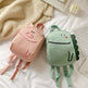 Two children's backpacks, one pink and one green, on a light surface.