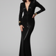 A model wearing a black long-sleeve floor-length gown with a deep plunging V-neckline and ruched detailing, accessorized with gold cuffs, against a neutral gray studio background.