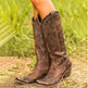 Brown cowboy boots with studded details on a grassy background