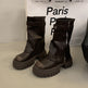 Pair of black leather boots with zippers on a light background