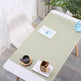 Light green desk pad on a wooden desk with a cup, saucer, and small plant in a room.