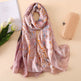 Decorative scarf with floral pattern on a beige surface with flowers and a clutch.