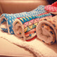 Roll-up fleece blankets with colorful patterns on a soft surface