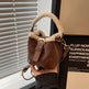 Brown handbag with fur trim held in front of a window with blinds.