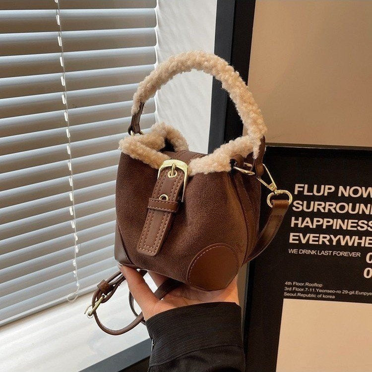 Brown handbag with fur trim held in front of a window with blinds.