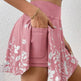 Person wearing a pink skirt with floral patterns against a white background
