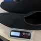 Schwarze Schuhe werden auf einer digitalen Waage gewogen mit unscharfem Hintergrund
