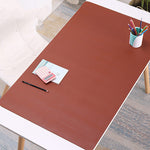 Brown desk mat on a white table with stationery items in a home office setting
