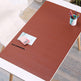 Brown desk mat on a white table with stationery items in a home office setting
